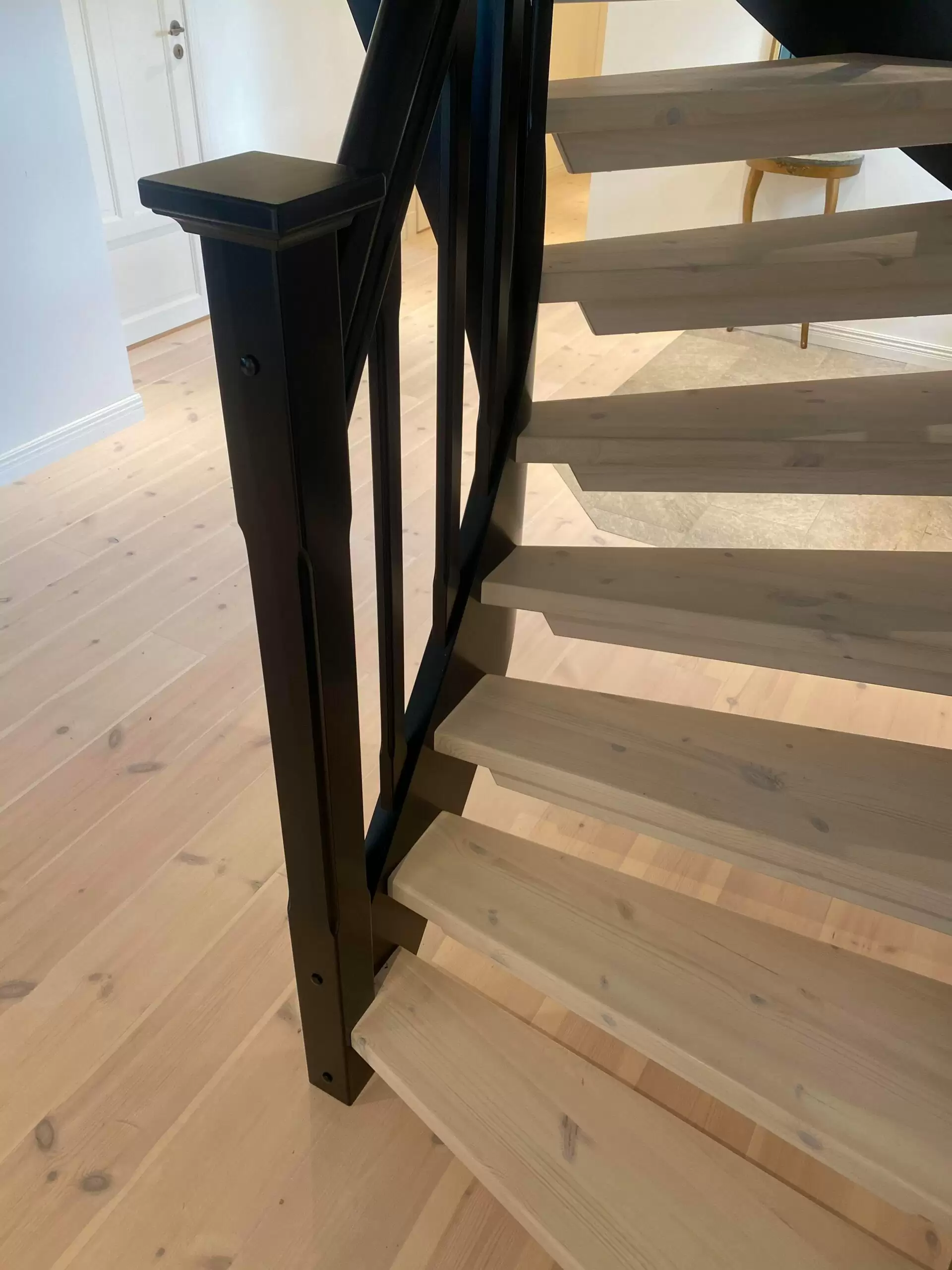 ljus trätrapp, med svart räcke, samma stil som parketten